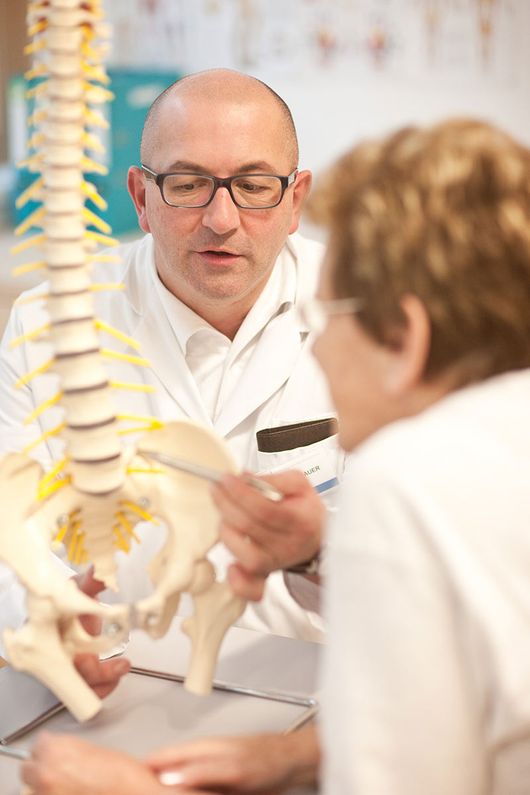Orthopäde im Bezirk Hallein zeigt Patientin ein Skelett